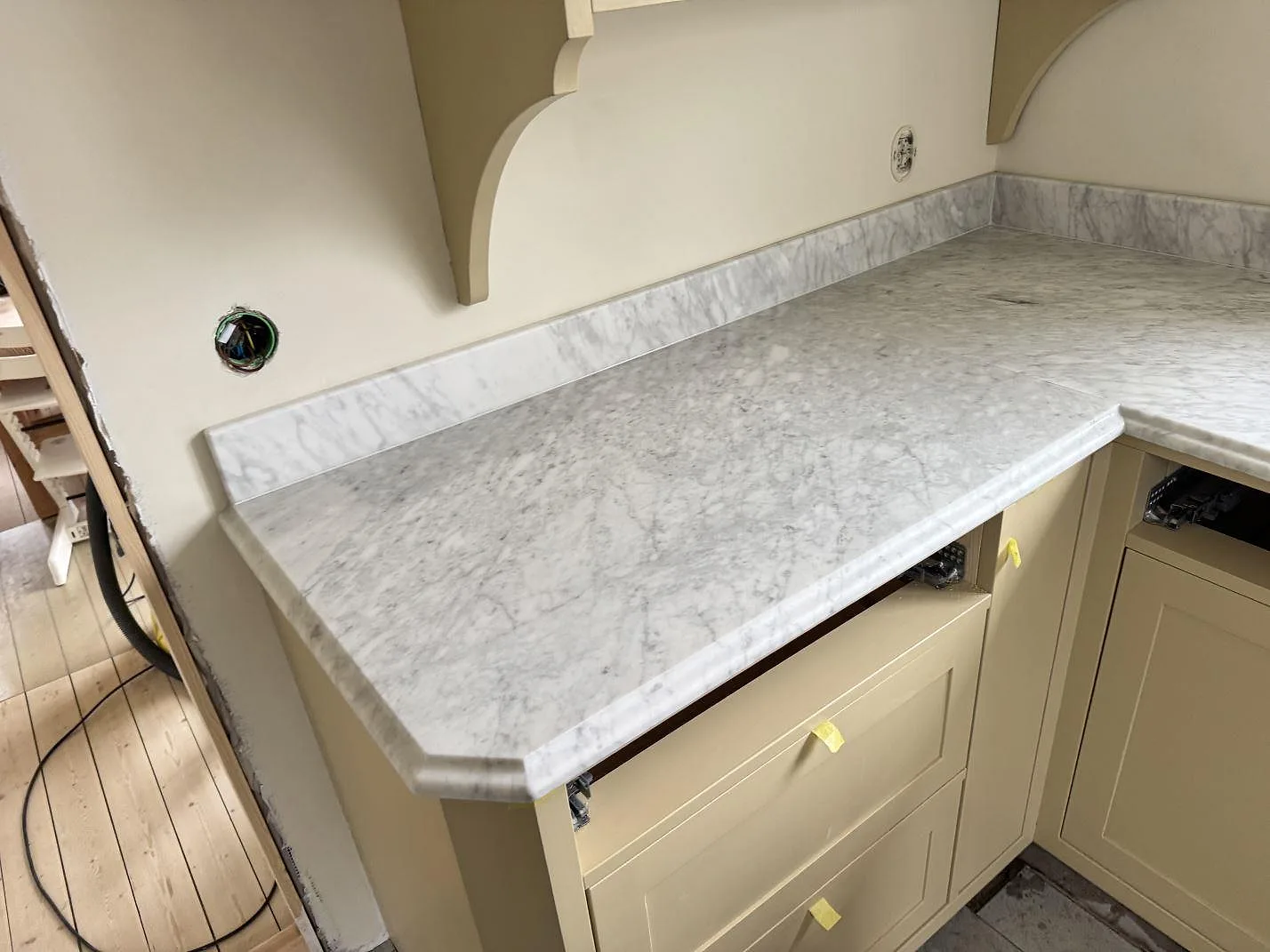 Matt köksbänkskiva i Carrara C marmor med uppvikt stänkkant och vinklad vänsterdel i ett kök i Råå.