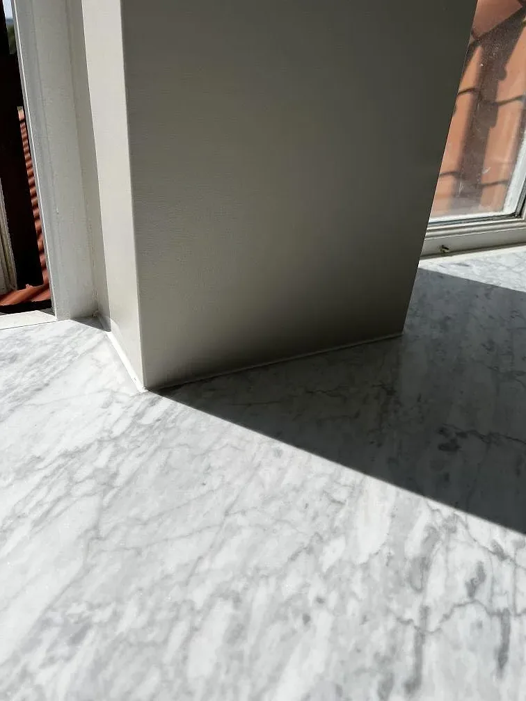 Närbild på ljus matt Carrara C marmor med grå ådring runt fönster och väggbeklädnad i Rydsgård.