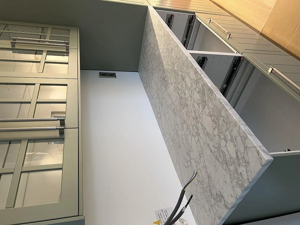 Vattenfallsida på köksö i matt Carrara C marmor intill grå köksstommar i Skanör.