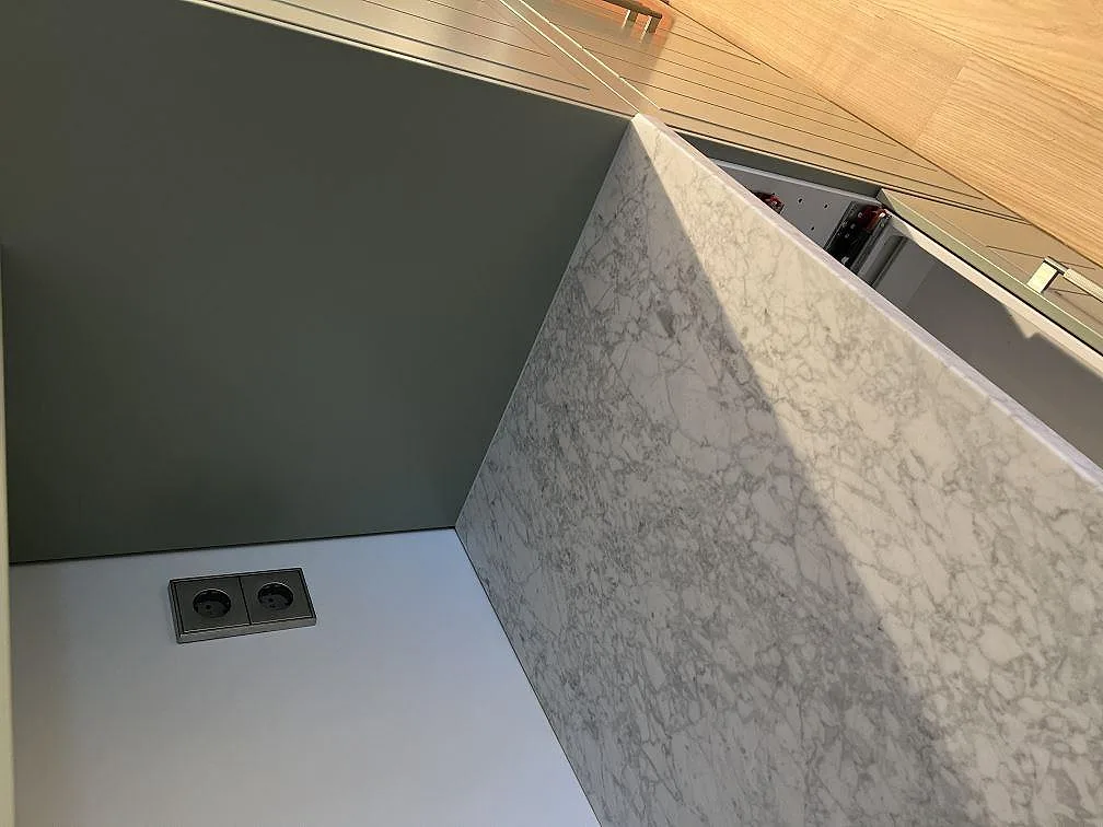 Detalj av matt Carrara C marmor på köksö med tät grå ådring och monteringsarbete i Skanör.