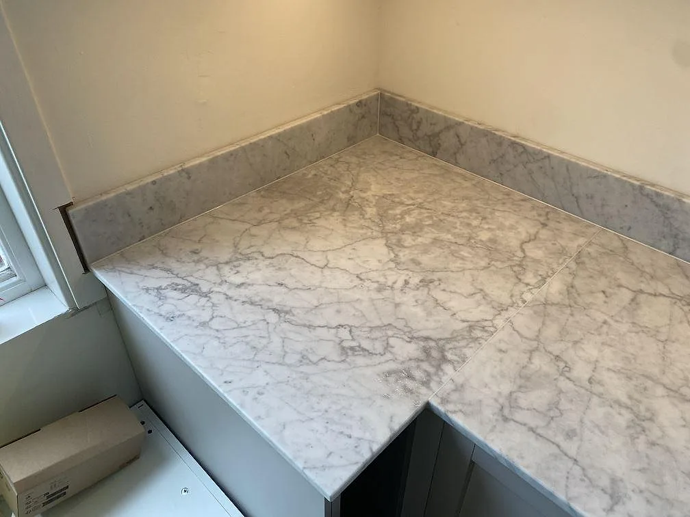 Hörndel av L-formad köksbänkskiva i matt Carrara C marmor med stänkkant i Skummeslövsstrand.