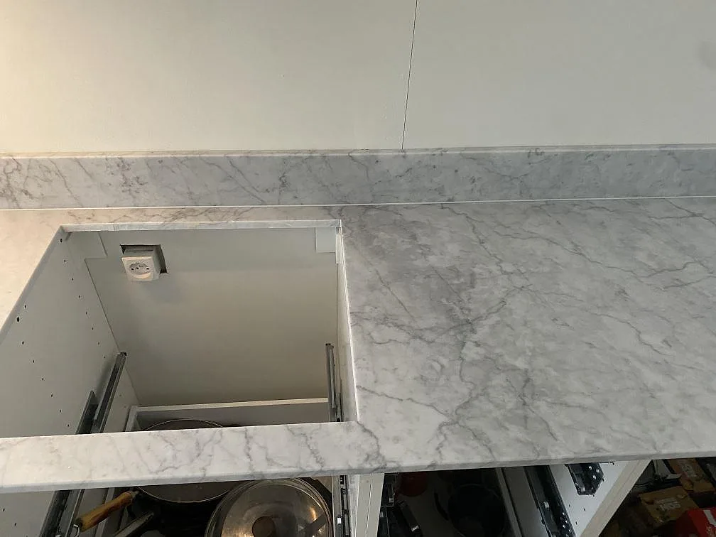 Detalj av Carrara C marmorbänkskiva i matt finish med hällurtag och öppen köksstomme i Skummeslövsstrand.