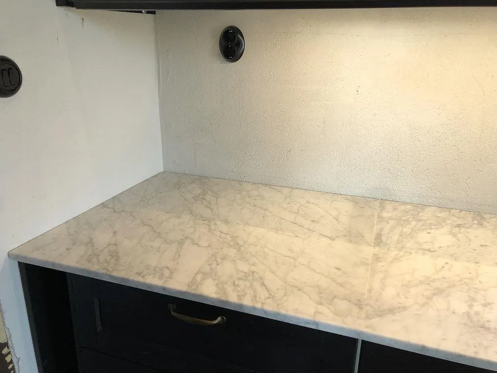 Närbild på bänkskivan i Carrara C-marmor med naturlig grå ådring i ett kök i Skurup.