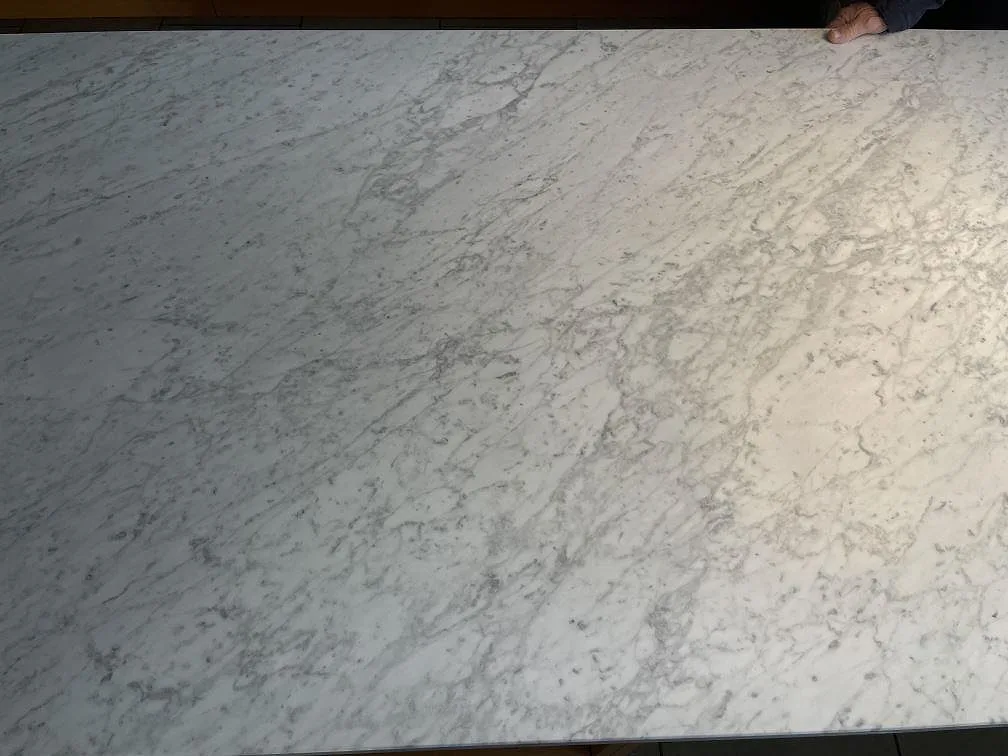 Detalj av den matta Carrara C-marmorns rörliga ådring på köksön i ett kök i Spånga.