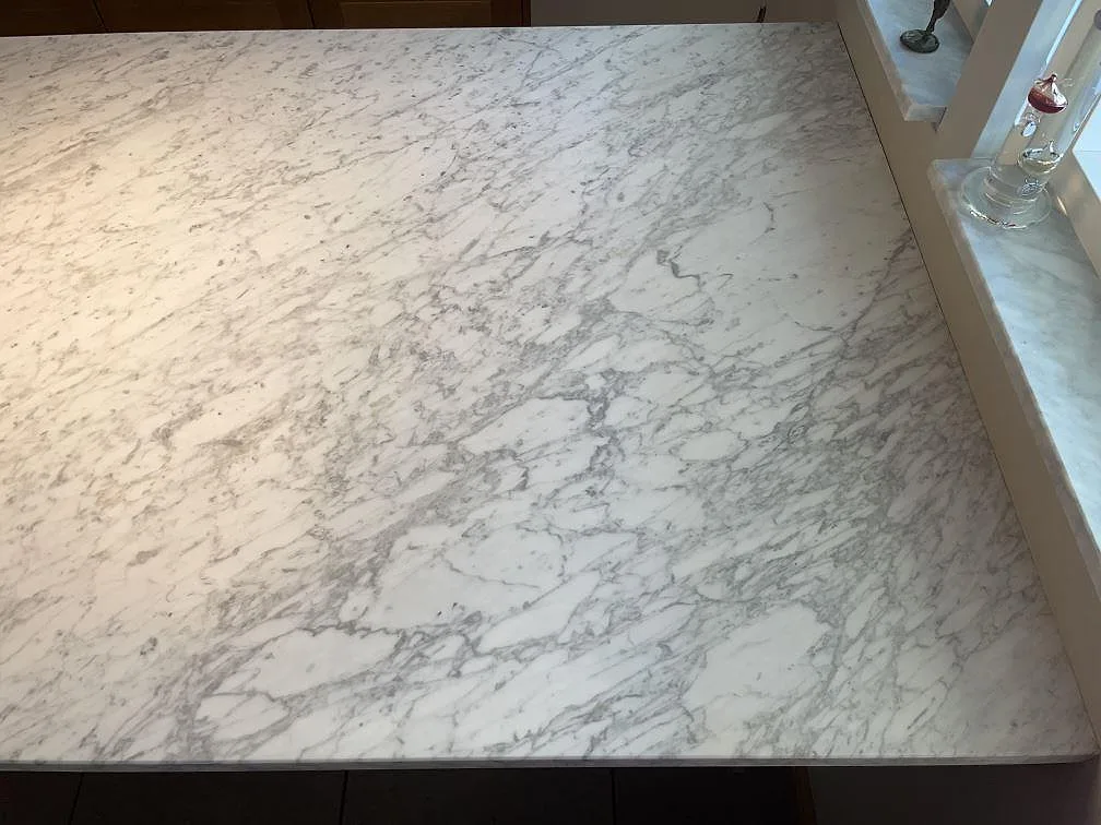 Närbild på den matta Carrara C-marmorns naturliga grå ådring i ett hörn av köksbänkskivan i ett kök i Spånga.