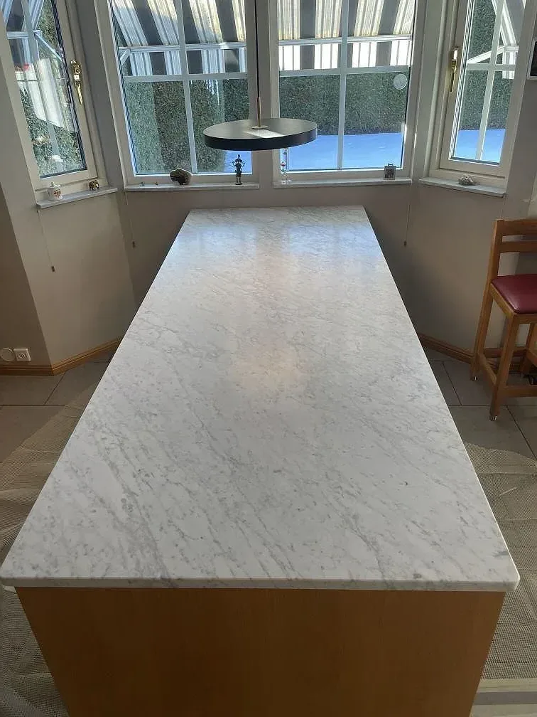 Köksö i matt Carrara C-marmor på en ekstomme i dagsljus i ett kök i Spånga.