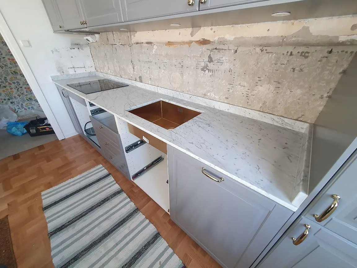 Bänkrad i Carrara C marmor med tydlig ådring längs väggen i ett kök under montering i Stockholm.