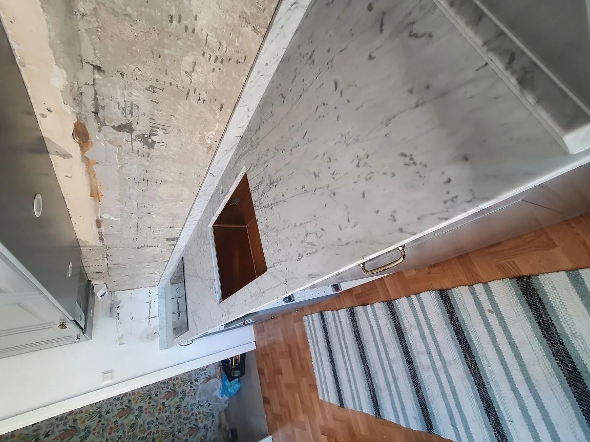 Matt Carrara C marmor som köksbänkskiva med underlimmad diskho och induktionshäll i ett kök i Stockholm.