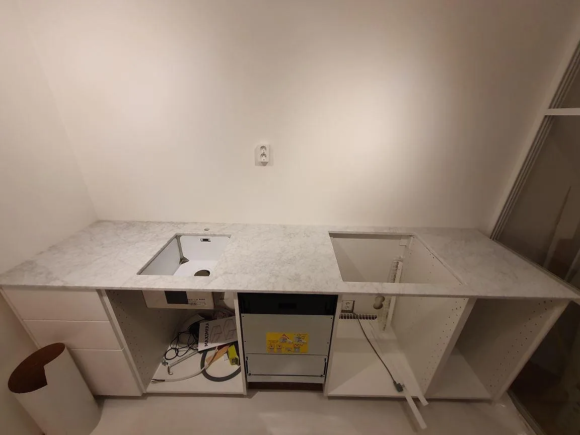 Matt köksbänkskiva i Carrara C marmor, 20 mm, med synliga öppningar i ett kök under montering i Stockholm.