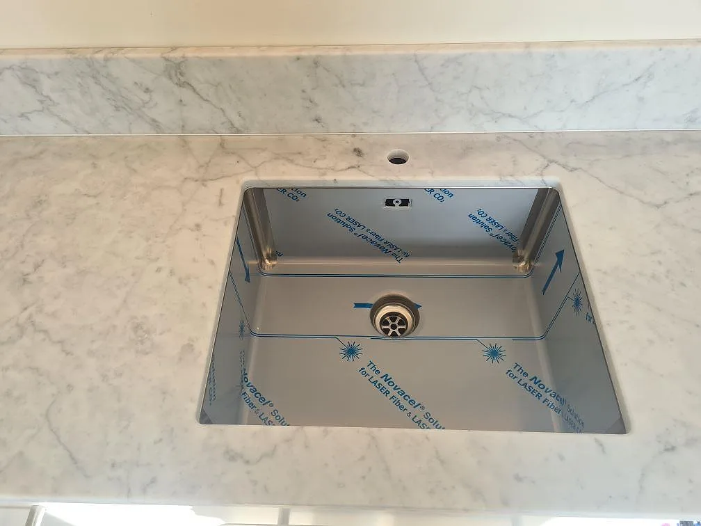 Underlimmad rostfri diskho i matt Carrara C marmorbänkskiva med blandarhål och stänkkant i Stockholm.