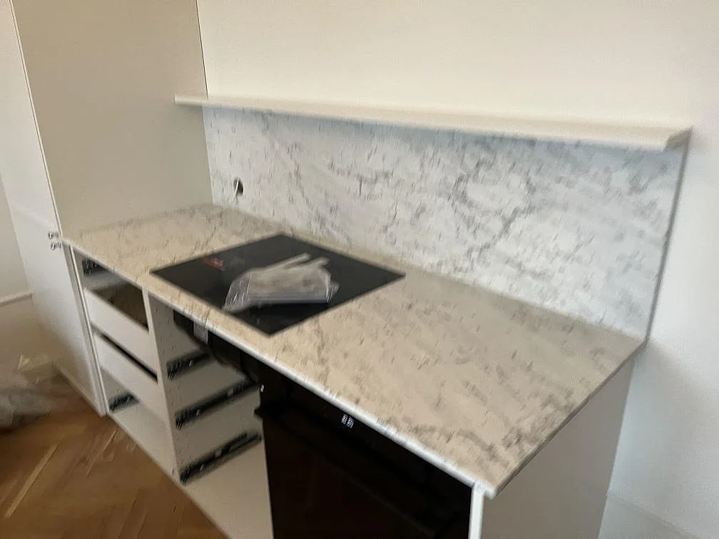 Köksbänkskiva i matt Carrara C marmor med häll och matchande marmorstänkskydd i ett kök i Stockholm.
