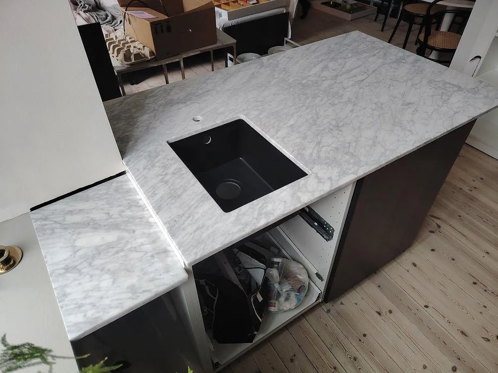 Matt Carrara C marmorskiva på köksö i Stockholm, sedd ovanifrån med svart diskho, kranhål och tydlig grå ådring.