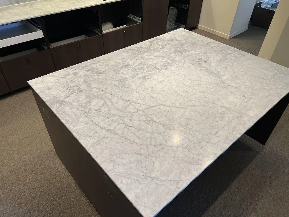 Närbild på köksö med matt Carrara C marmor, grå ådring och tunn 20 mm kant i Stockholm.