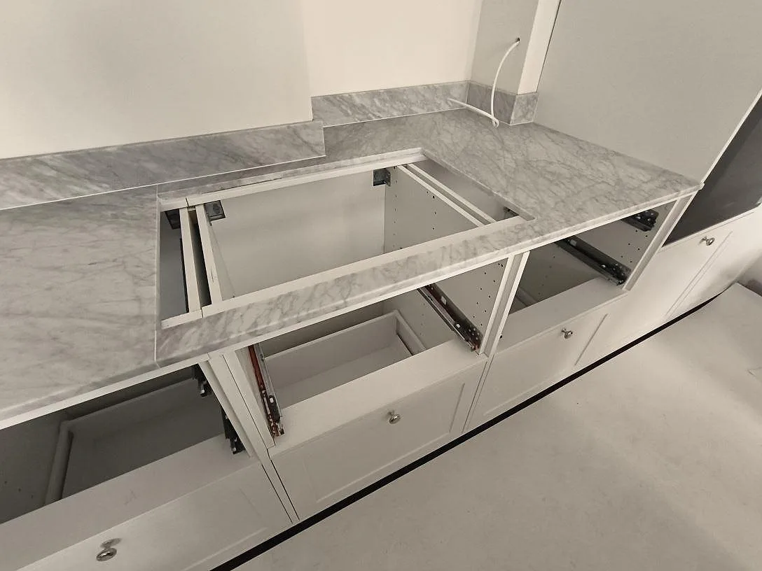 Hällurtag i en matt köksbänkskiva av Carrara C marmor med uppvikt stänkkant längs väggen i ett stockholmskök.