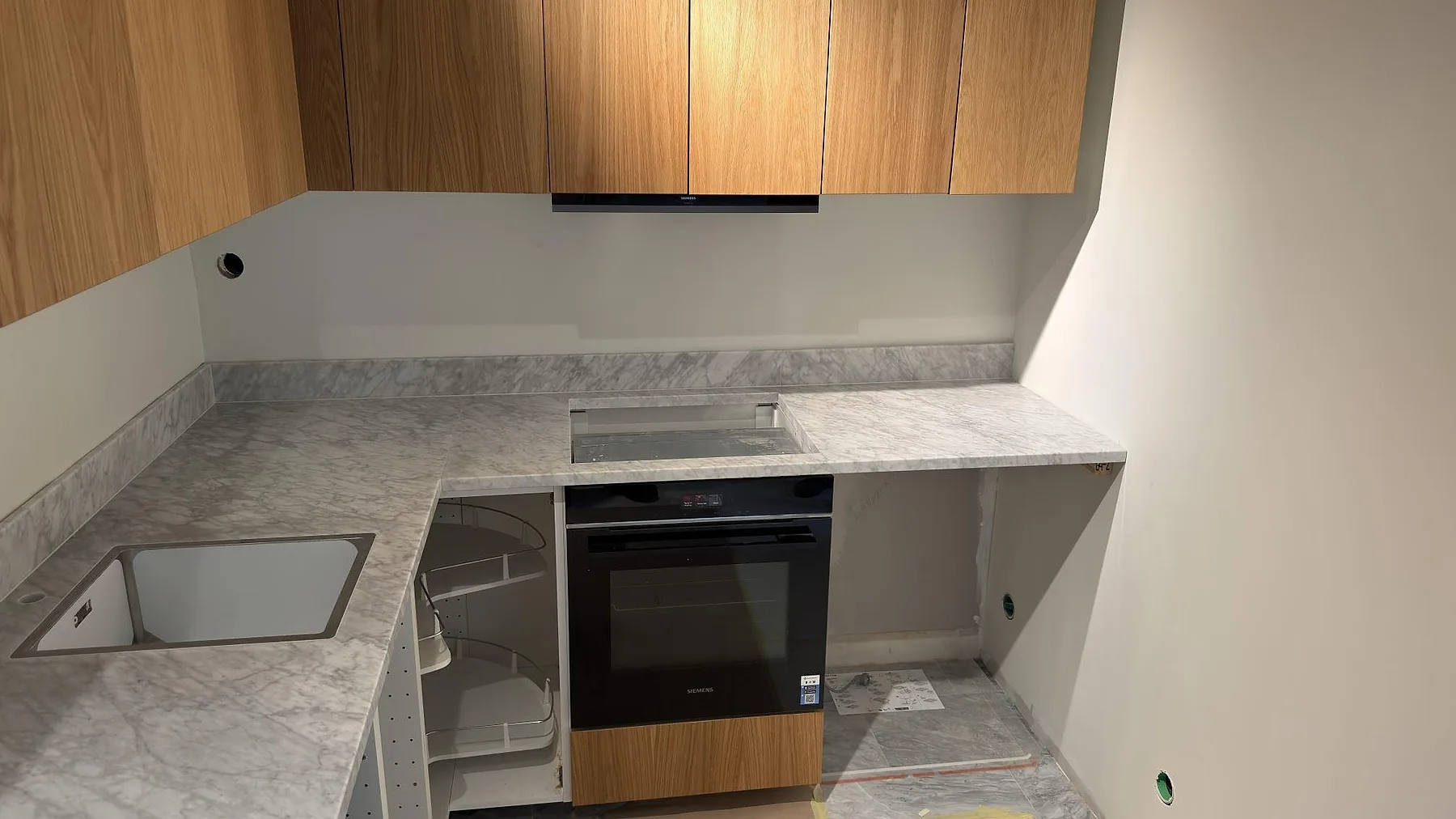 Matt Carrara C marmor i kök med hällöppning över ugn, diskho och uppvikt stänkkant i Stockholm.