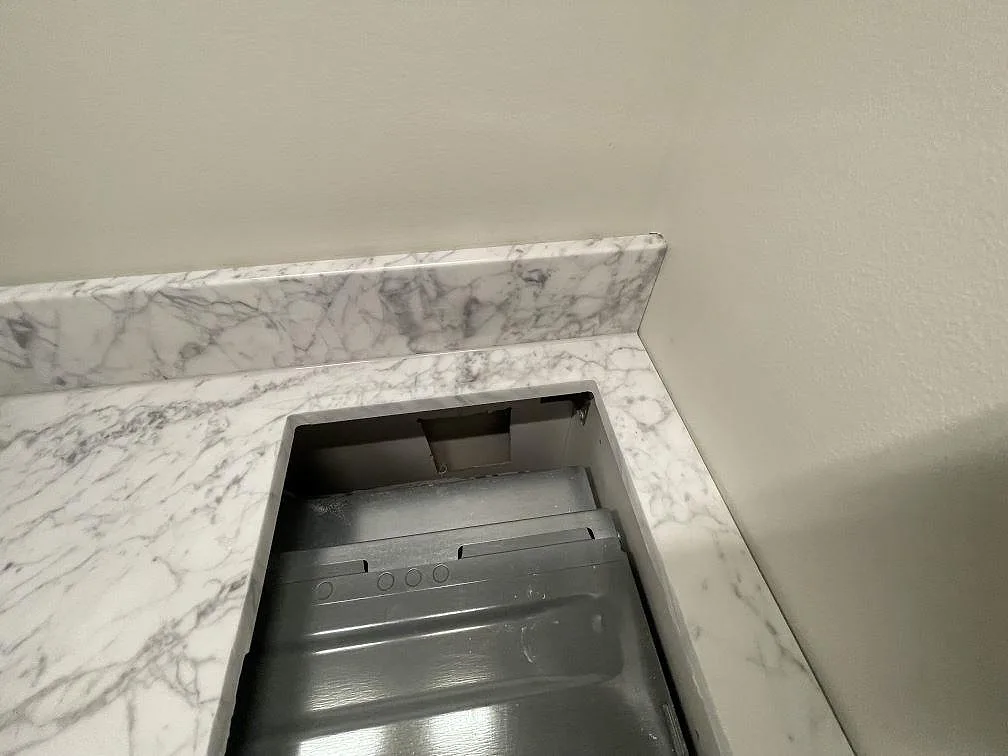 Hällurtag i polerad Carrara C marmor med uppvikt stänkskydd och tät ådring i ett kök i Stockholm.