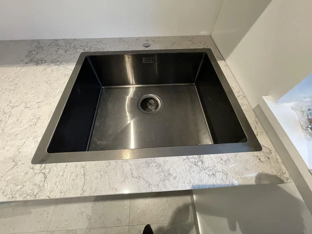 Diskhodetalj i polerad Carrara C marmor med blank stenram och ådrad bänkskiva i Stockholm.