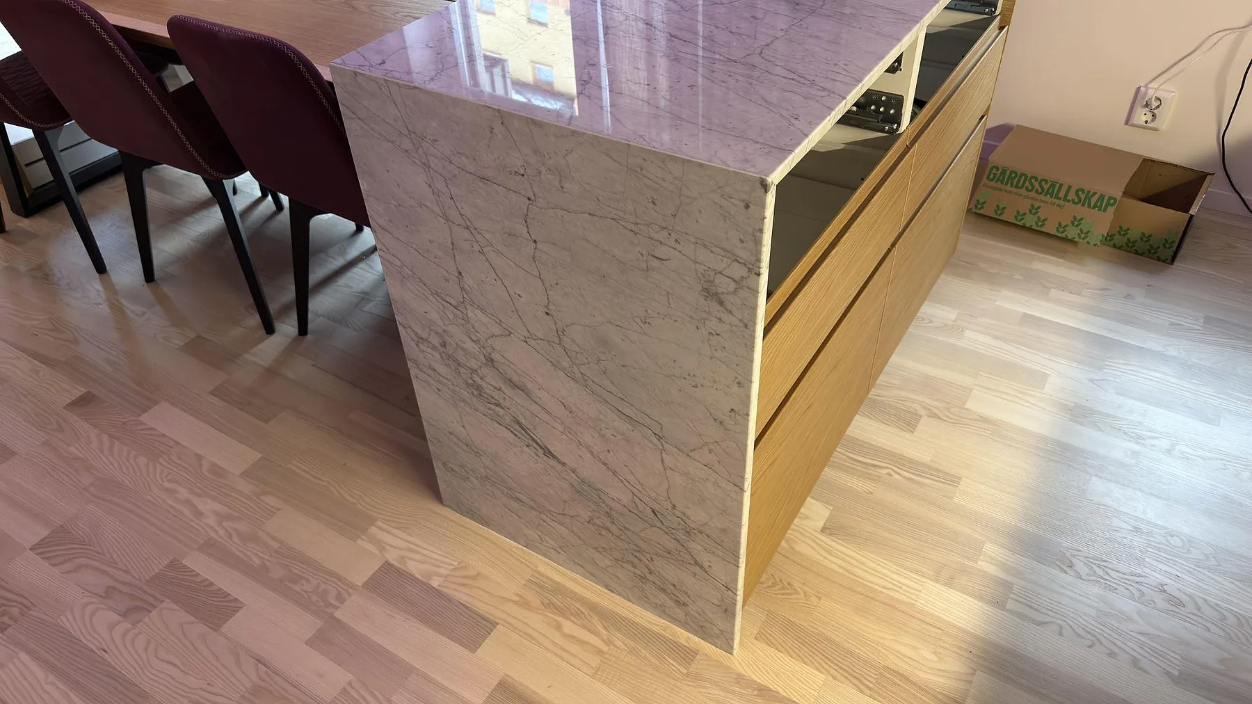 Sidovy av köksö med vattenfallsgavel i polerad Carrara C-marmor och träfronter i Stockholm.