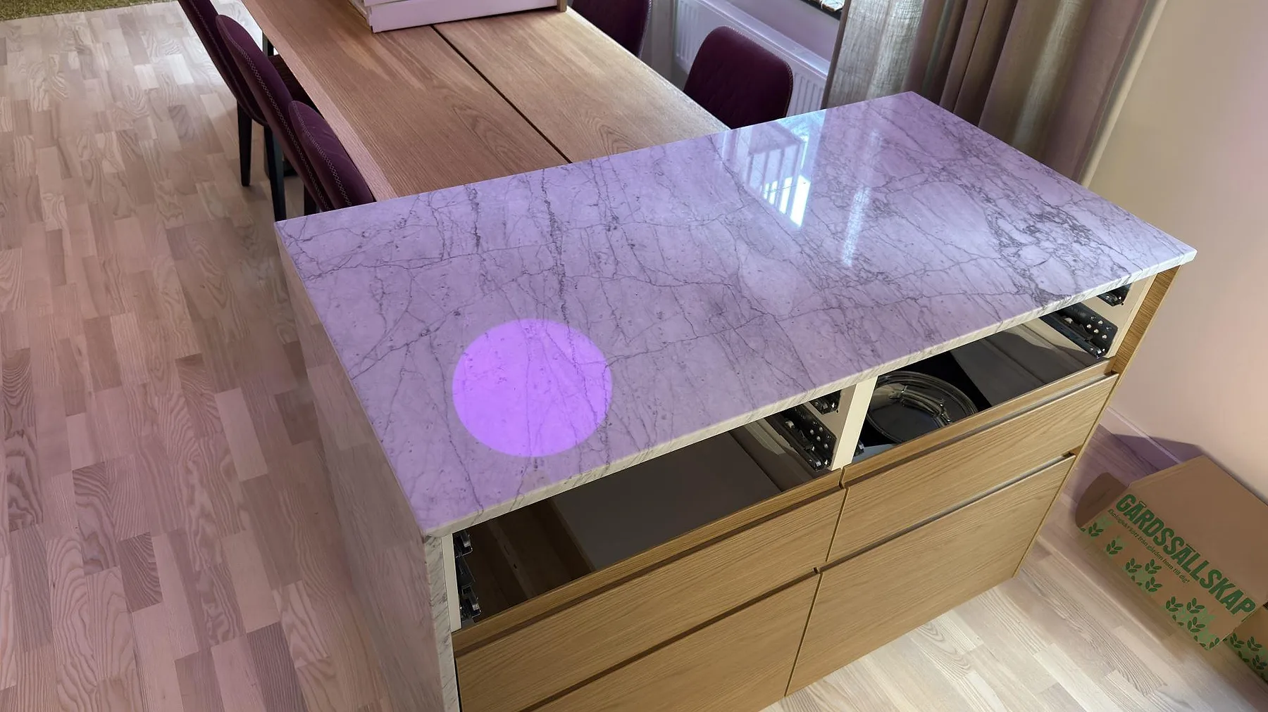 Toppskiva i polerad Carrara C-marmor med tydliga ljusreflexer och grå ådring på köksö i Stockholm.