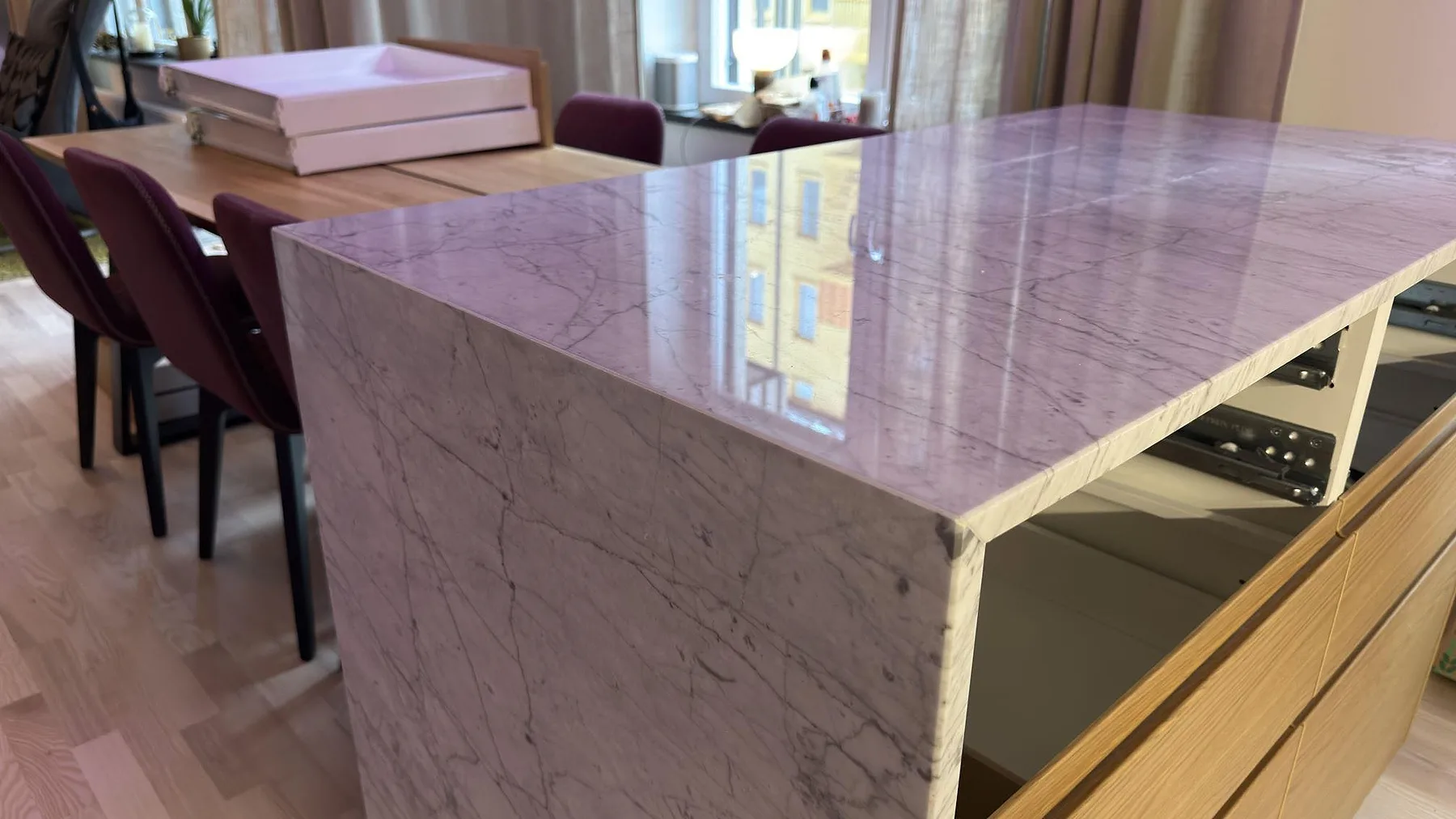 Närbild på polerad Carrara C-marmor med grå ådring över topp och gavel på en köksö i Stockholm.