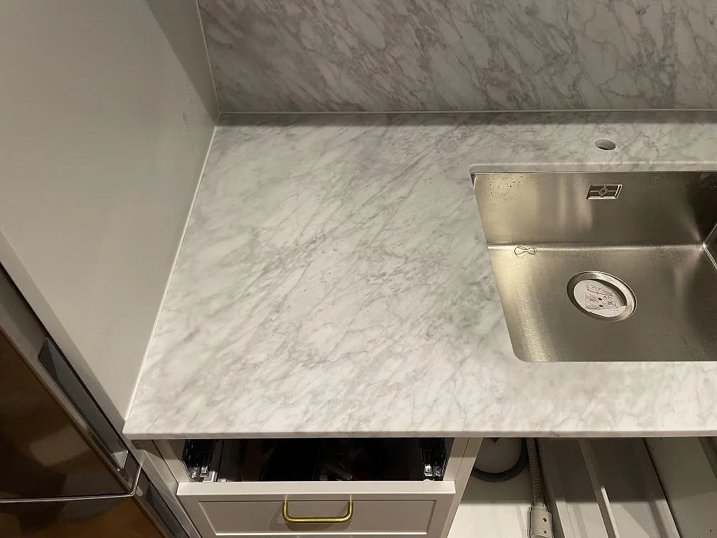 Detaljbild av Carrara C marmor, matt, vid diskho och stänkskydd med synlig ådring i Stockholm.