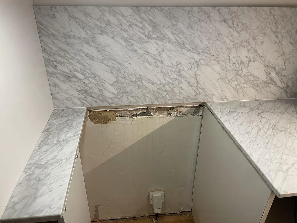 Installerad bänkskiva och stänkskydd i Carrara C marmor i ett kök under montering i Stockholm, vit marmor med diskret grå ådring.