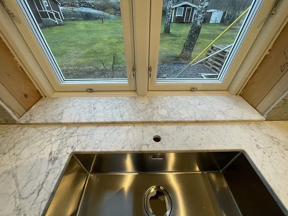 Bänkskiva i Carrara C marmor med tydlig grå ådring, matt yta, monterad i situ under installationen i ett hem i Stora Höga.