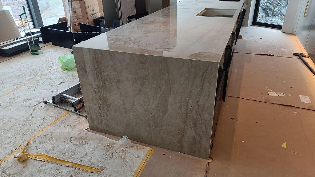 Köksö med vattenfallsida i polerad Carrara C marmor, 20 mm, under montering i ett kök i Stora Höga.