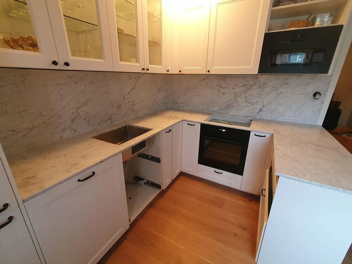 Närbild på matt Carrara C-marmor med underlimmad rostfri diskho och grå ådring i ett kök i Sundbyberg.