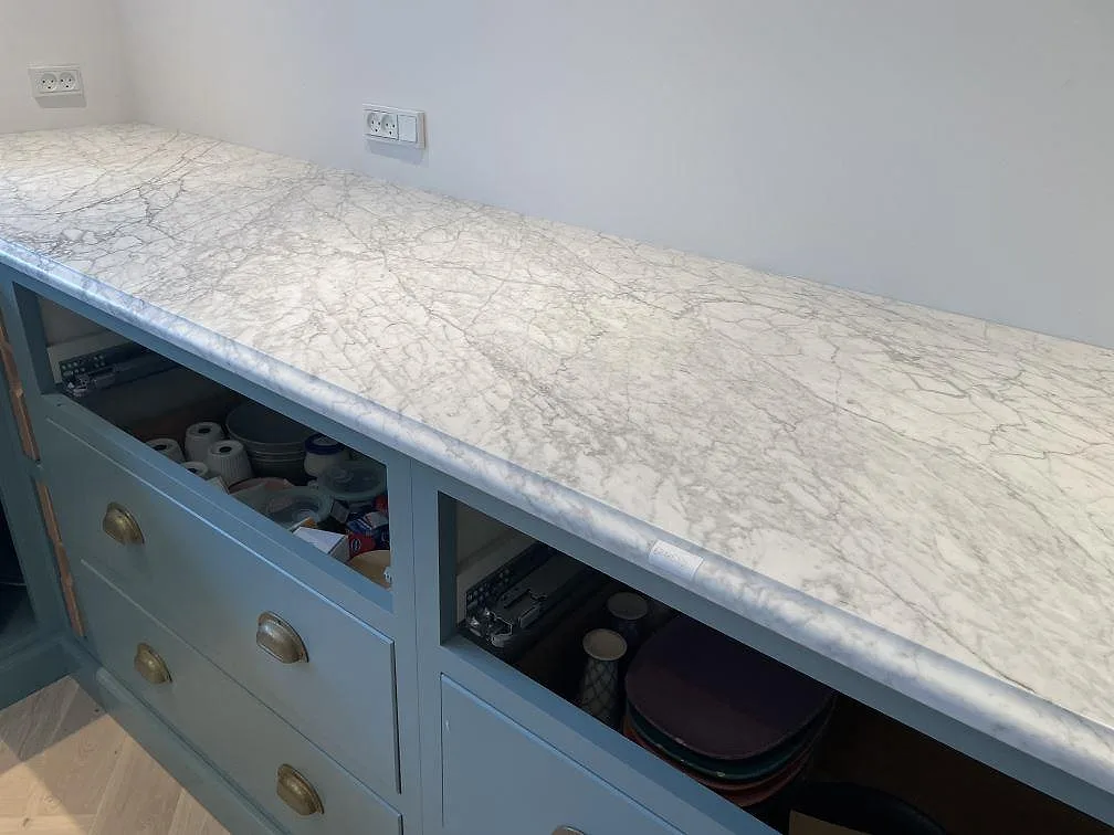 Köksbänkskiva i Carrara C marmor, matt, som lång arbetsyta på blågröna skåpstommar i Tisvilde.