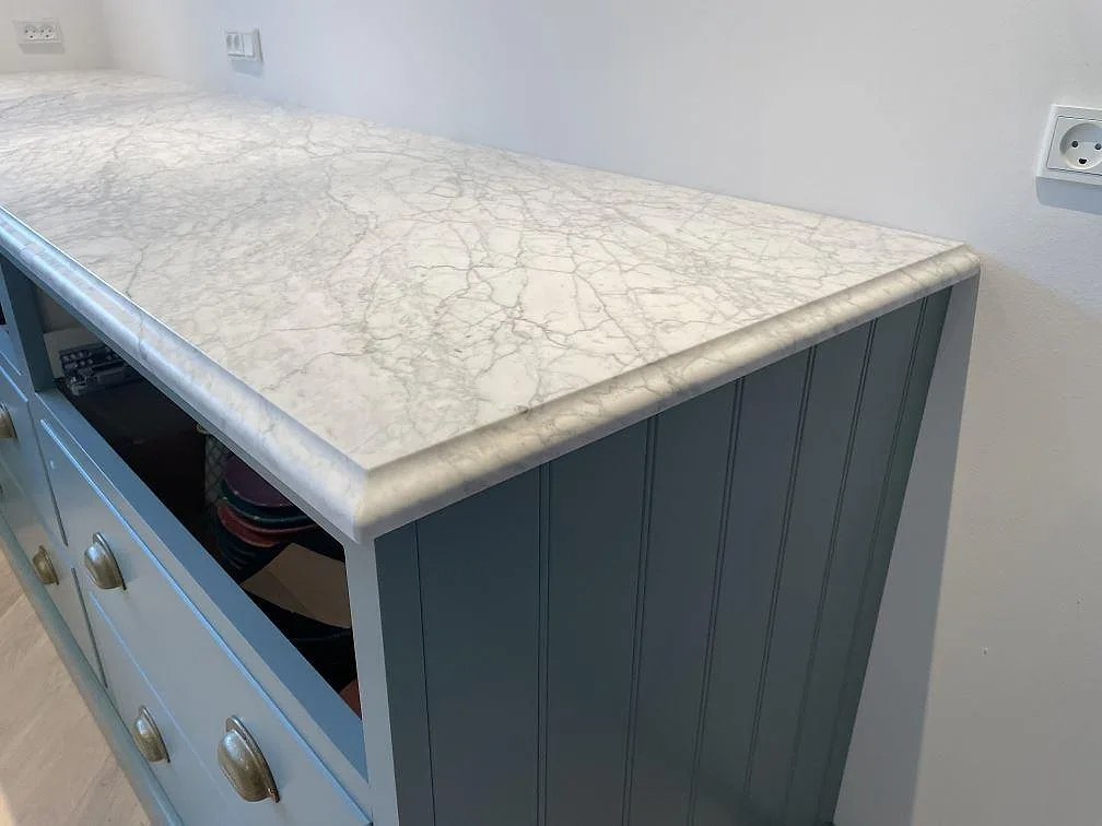 Detalj av matt Carrara C marmor med profilerad kant på blågrön köksstomme i Tisvilde.