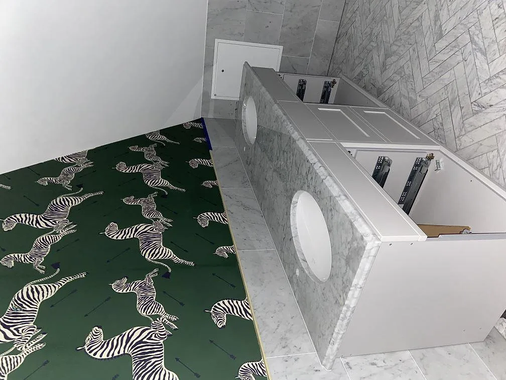Badrumsbänkskiva i polerad Carrara C-marmor med dubbla underlimmade ovala tvättställ, monterad under pågående installation i ett badrum i Torekov.