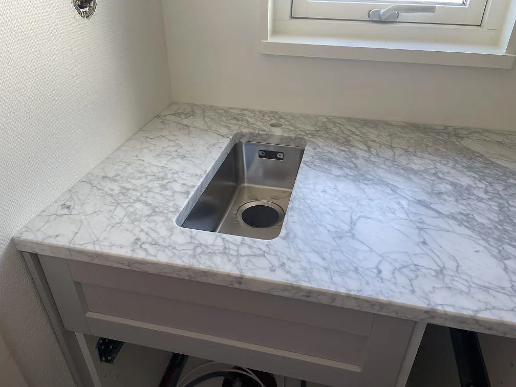 Mindre rostfri diskho i matt Carrara C marmor vid fönster i tvättdelen i Torekov.