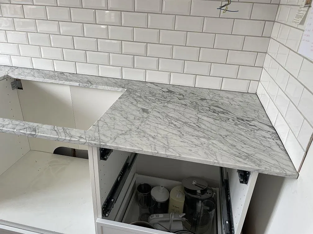 Carrara C köksbänkskiva, matt marmor, med urtag för rostfri diskho och vit kaklad vägg i Trelleborg.
