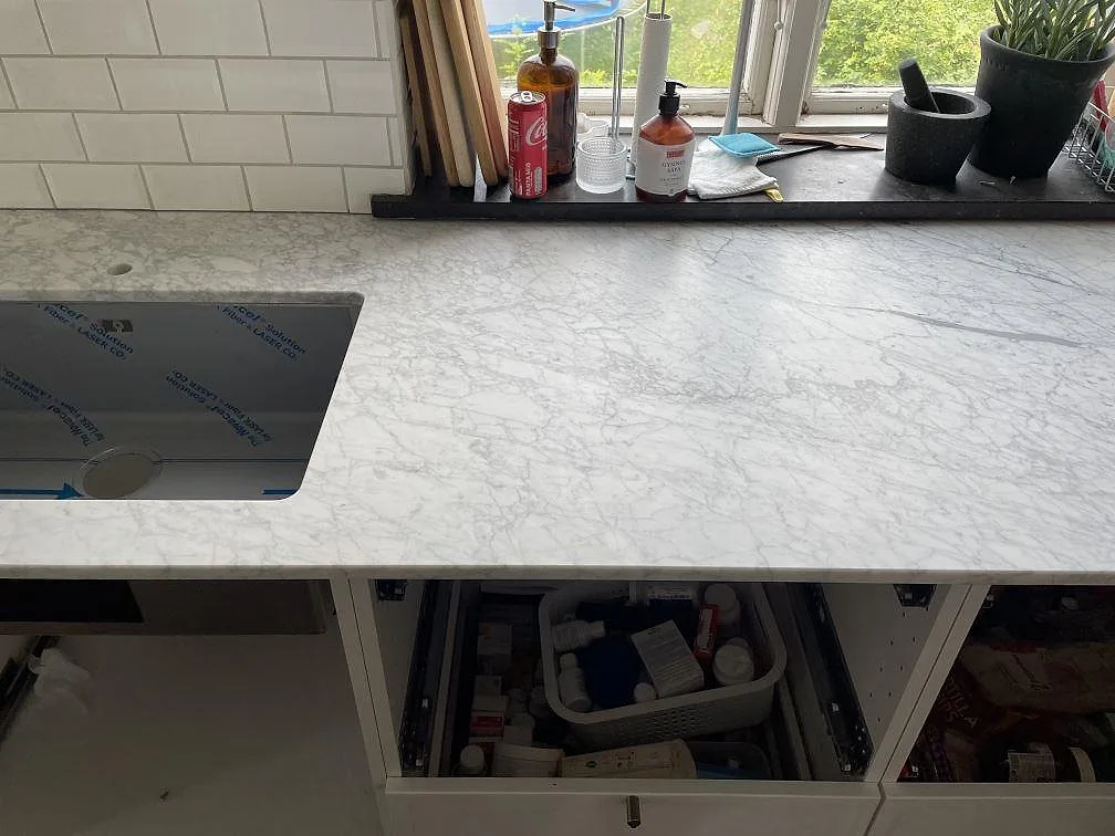 Matt Carrara C marmorbänkskiva vid fönster med underlimmad rostfri diskho och vita köksstommar i Trelleborg.
