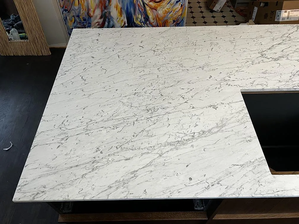 Närbild av köksö i Carrara C marmor, 20 mm, med livlig grå ådring och hällurtag i Trelleborg.