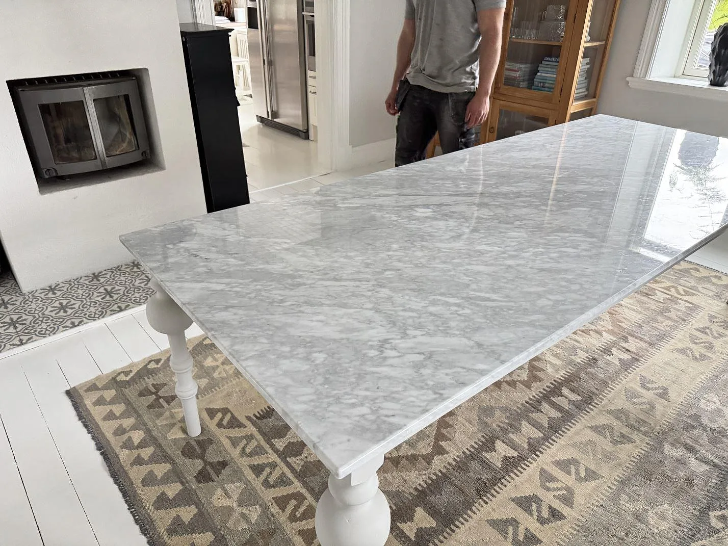 Polerad Carrara C marmor som bordsskiva nära en öppen spis, med tydlig grå ådring i Trollhättan.