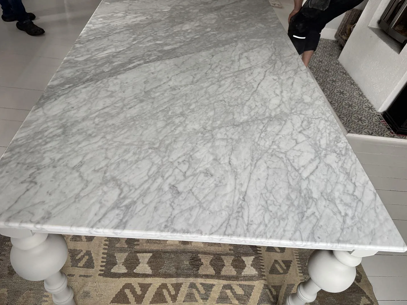 Detaljbild av Carrara C marmor som bordsskiva, polerad yta och rundade vita bordsben i Trollhättan.