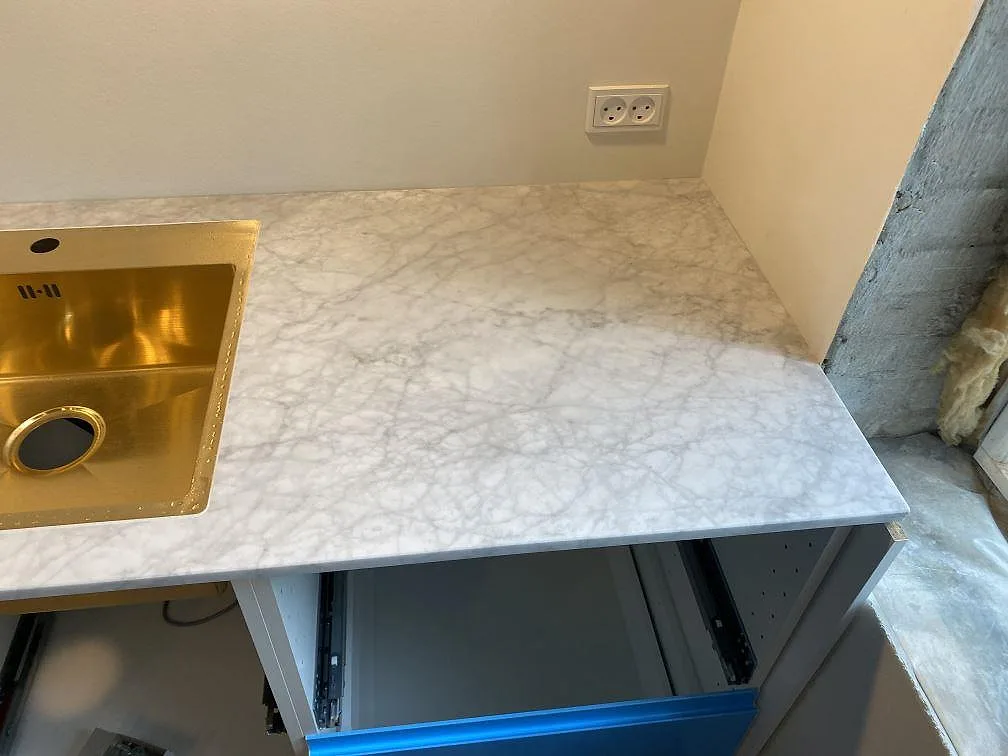 Underlimmad diskho i mässingston i en köksbänkskiva av vit Carrara C marmor i Valby.