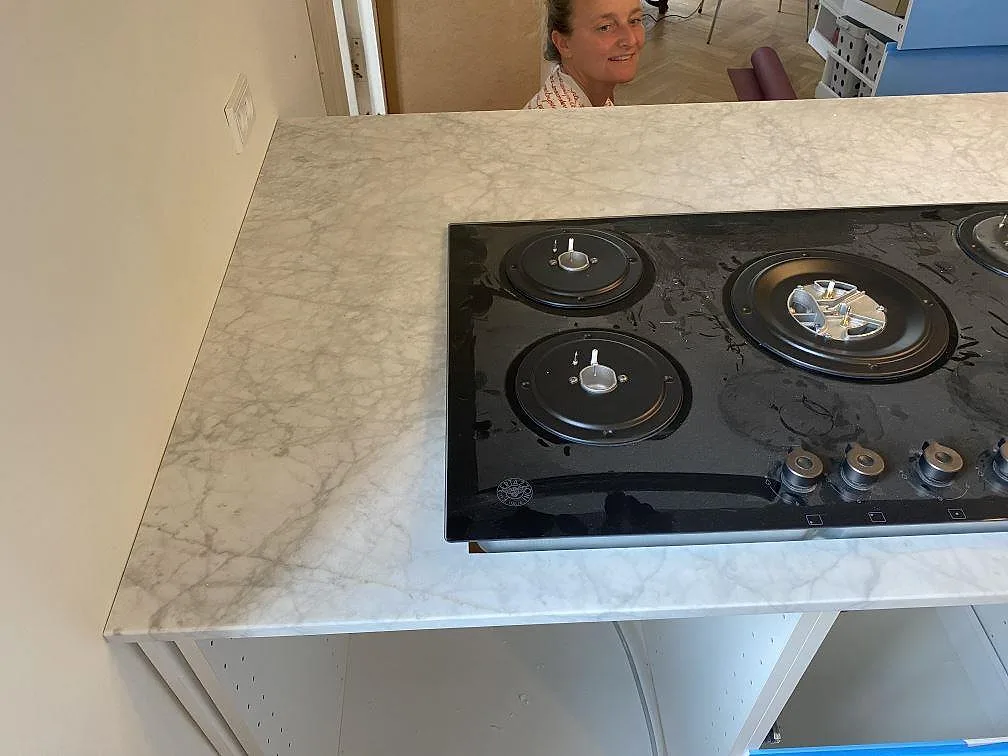 Gashäll installerad i en köksö av vit Carrara C marmor med tydlig grå ådring i ett kök i Valby.