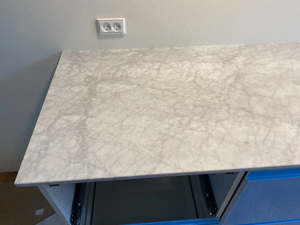 Köksbänkskiva i vit Carrara C marmor med grå ådring ovanifrån, matt yta, i ett kök i Valby.