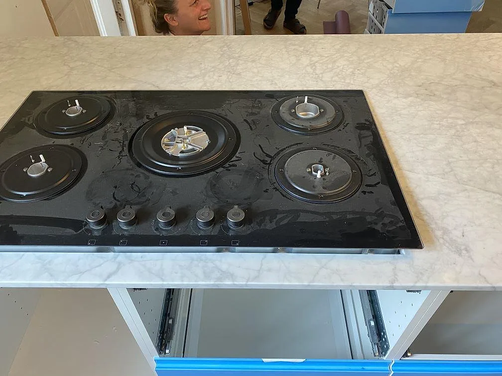 Gashäll med fem brännare i en köksö av vit Carrara C marmor i ett kök i Valby.