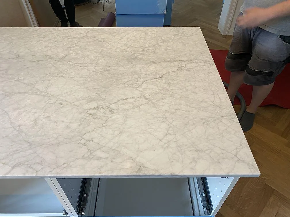 Köksö i vit Carrara C marmor med grå ådring, matt yta, ovanifrån i ett kök i Valby.