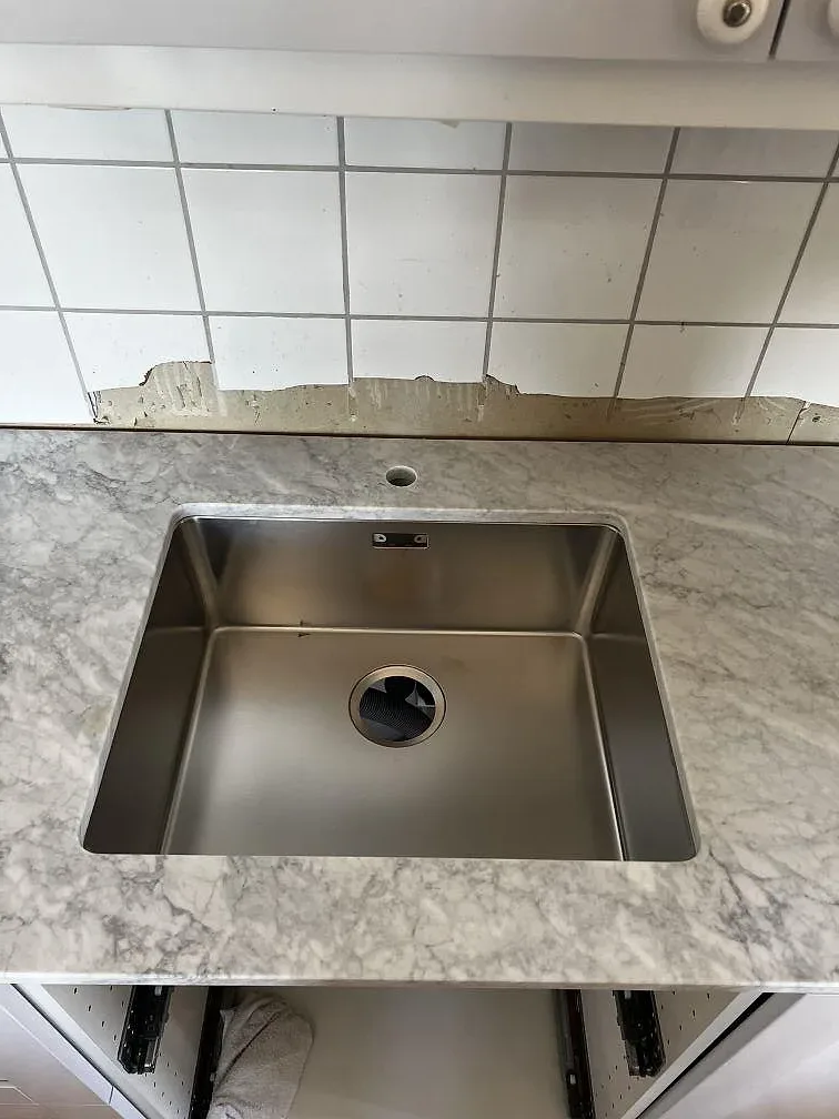 Närbild på matt Carrara C marmorbänkskiva med underlimmad rostfri diskho och hål för blandare i Hunnebostrand.