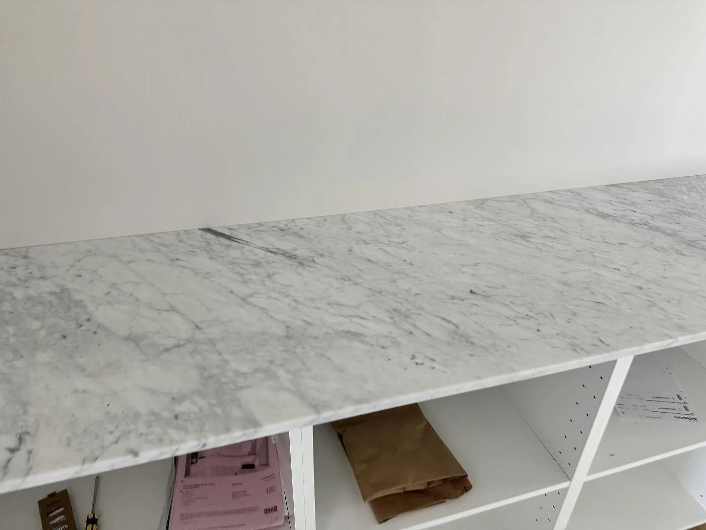 Frontvy av matt Carrara C marmorbänkskiva med rak framkant över öppna köksstommar i Klippan.