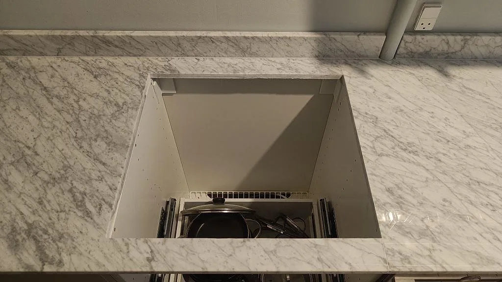 Detalj av rektangulärt urtag i polerad Carrara C marmorbänkskiva med tydlig grå ådring i ett kök i København S.