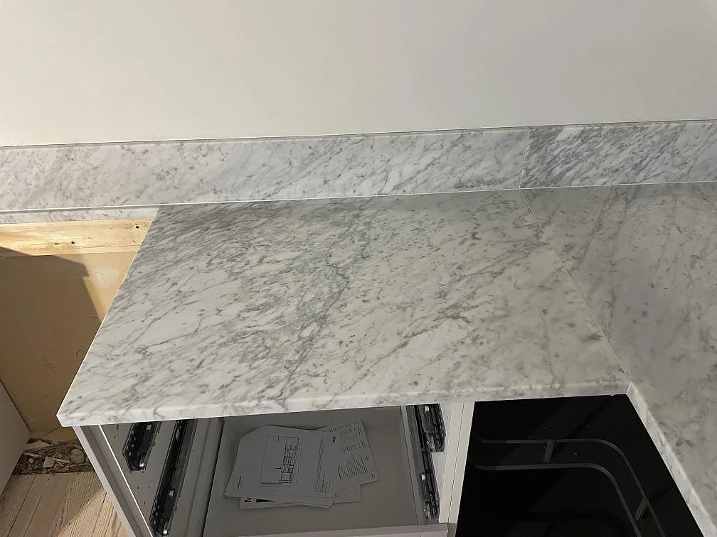 Närbild av bänkskivans hörn i matt Carrara C med ådrad marmoryta och låg stänkkant i Lund.