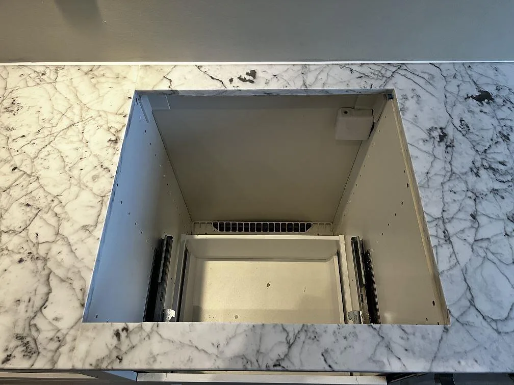 Hälluttag i matt Carrara C marmor med tydlig mörkgrå ådring och grå köksvägg i Malmö.