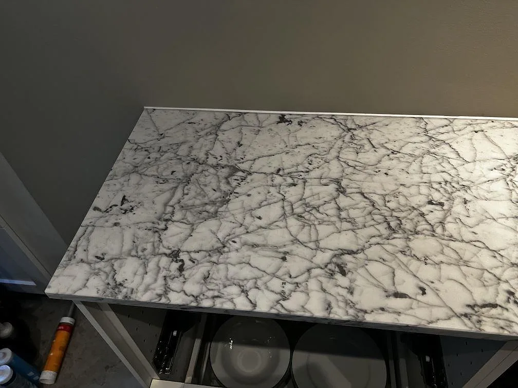 Topvy över matt Carrara C marmor med mörk ådring på en lång köksbänk under montering i Malmö.