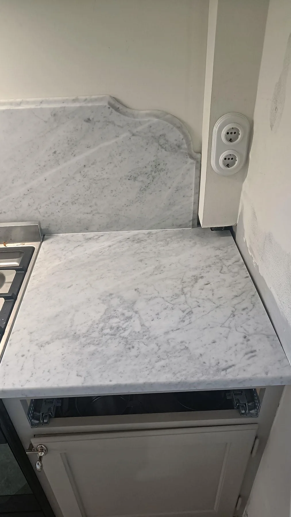 Detalj av matt Carrara C marmorbänkskiva och profilerad stänkkant vid vägguttag i Malmö.